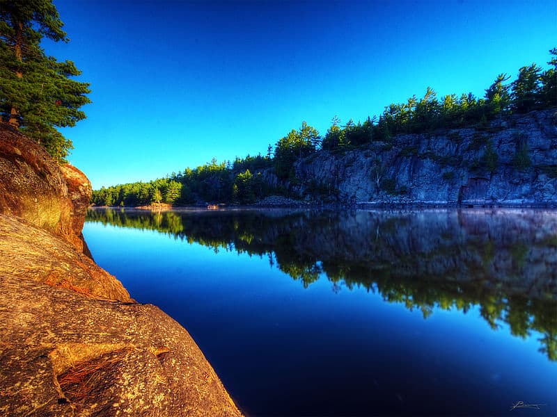 An impossibly blue river winds through red stone cliffs and dense forest (French River PP, Ontario)