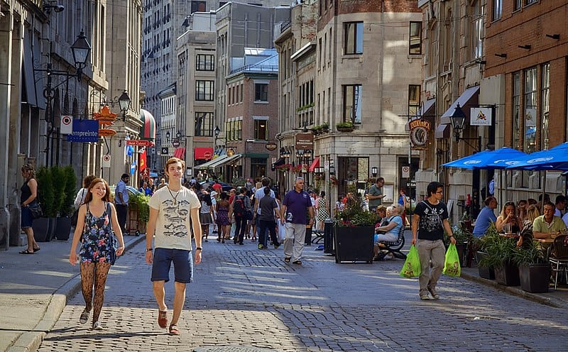 A young man and a woman walk on a busy cobblestone street in Montreal, Quebec.