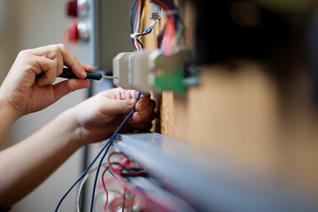 Photograph of electrical engineering technician working with wires.