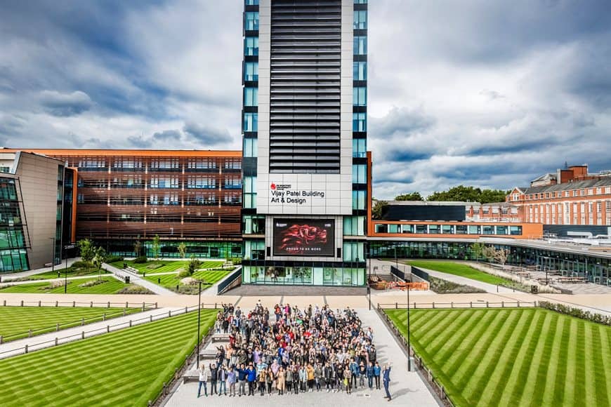 A photo of De Montfort University Leicester's campus with students standing outside.