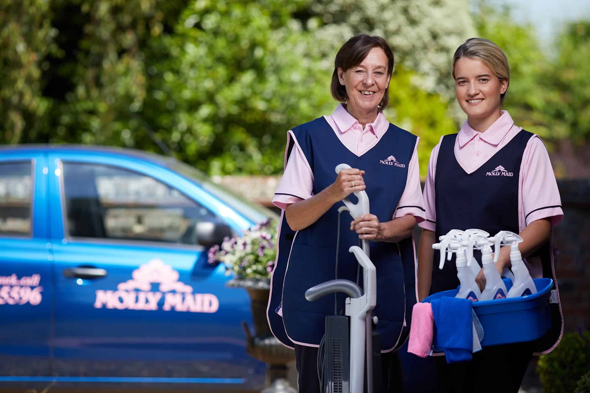 A photo of two Molly Maids with their cleaning supplies.