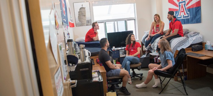 A group of students from the University of Arizona making the most of their dorm roomâs space with a folding cushion chair.