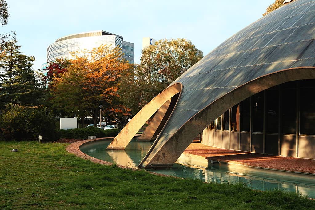 A domed roof building surrounded by a small moat, with a modern glass building in the background (Academy of Science, Australian National University)