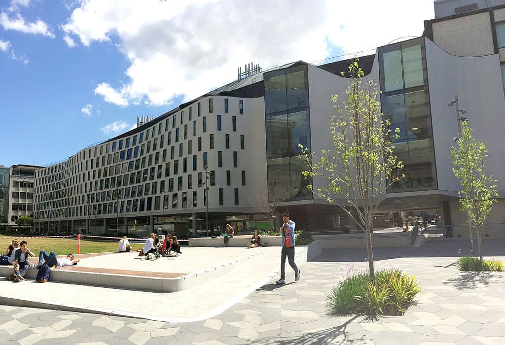 A courtyard view of a medium-height concrete and glass building, with students walking in the courtyard (Science and Grad School of Health Building, UTS)