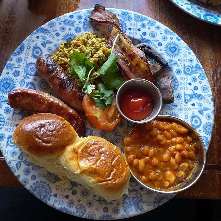 An "Irish Fry" breakfast: baked beans, eggs, sausage, grilled tomato, bacon, and mushrooms.