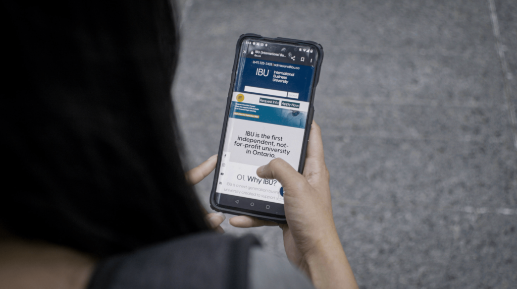 A woman holds a smartphone, on which the words "Why IBU?" are visible.