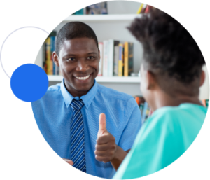 A man in a collared shirt and tie gives a thumbs-up to another student