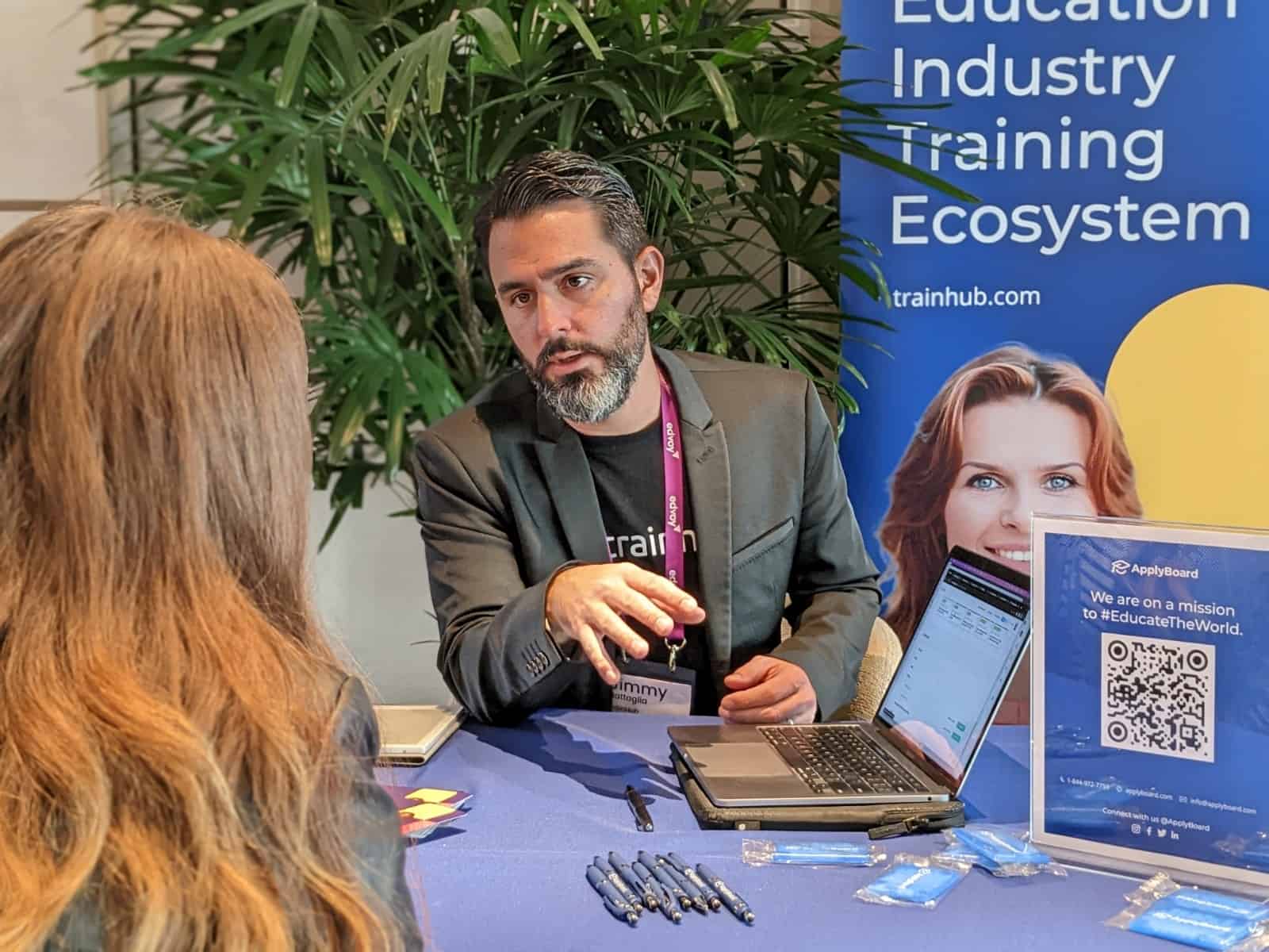 Jimmy Battaglia, Founder and Head of TrainHub speaking to a conference participant at the TrainHub booth in ApplyBoard's section.